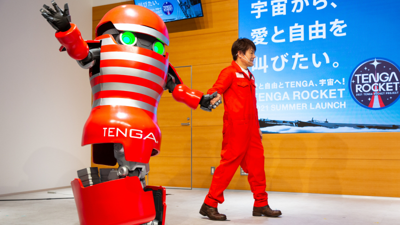 The TENGA ROBO waves goodbye to the crowd, holding hands with Koichi Matsumoto at the TENGA Rocket Press Conference